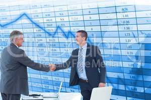 Happy businessmen shaking hands against stock data background
