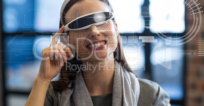 Digitally generated image of various graphics against woman using VR glasses in office