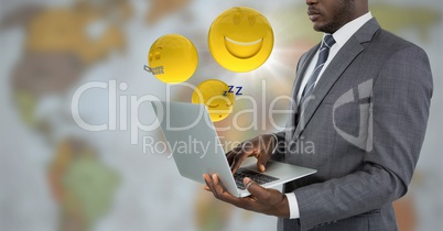 Business man with laptop and emojis with flare against blurry map