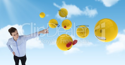 Digital composite image of businesswoman pointing at various emojis in sky