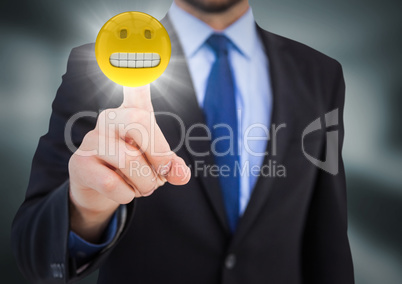 Business man pointing at emoji with flare in blurry grey room