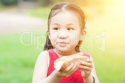 Asian child eating outdoors.