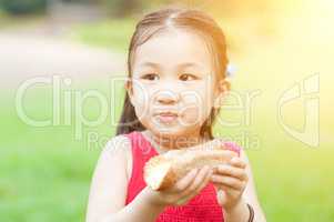 Asian child eating outdoors.