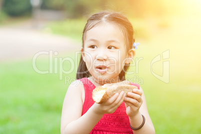 Asian kid eating outdoors.