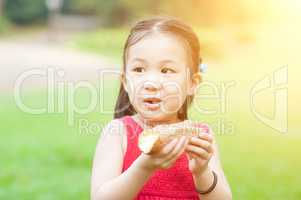 Asian kid eating outdoors.