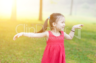Asian child dancing outdoors.
