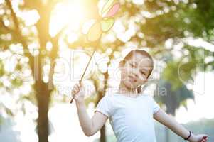 Asian child playing windmill outdoors.