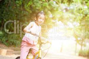Asian child riding bicycle outdoor.