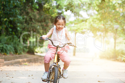 Active Asian child riding bicycle outdoor.
