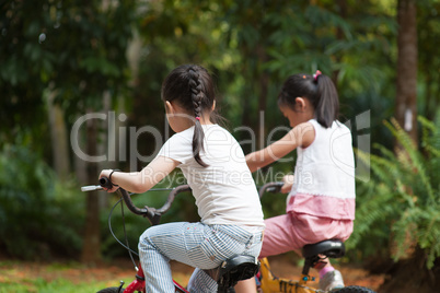 Active Asian children riding bicycle outdoor.