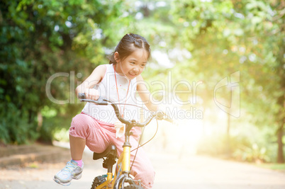 Active Asian child riding bike outdoor.