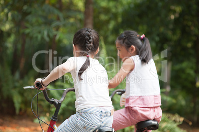 Active Asian children riding bike outdoor.