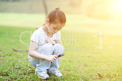 Child exploring nature with magnifier glass at outdoors.