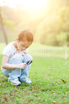 Kid exploring nature with magnifier glass at outdoors.