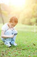 Kid exploring nature with magnifier glass at outdoors.