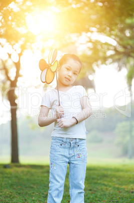 Asian kid playing windmill outdoors.