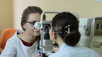 Optician with tonometer examining patient's eyes