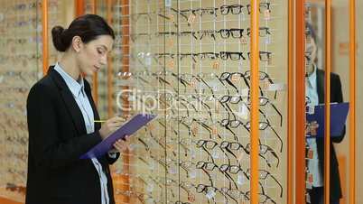 Pretty female optician revising glasses in optics