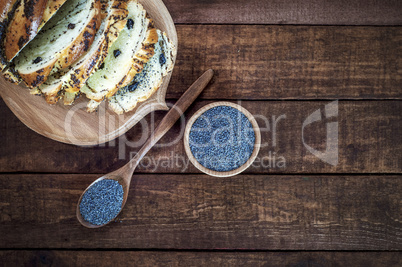 poppy seed in a wooden bowl and a spoon on a brown surface