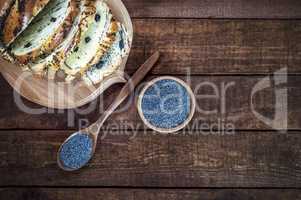 poppy seed in a wooden bowl and a spoon on a brown surface