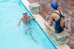 Senior man interacting with woman at poolside