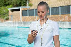 Swim coach looking at stopwatch near poolside