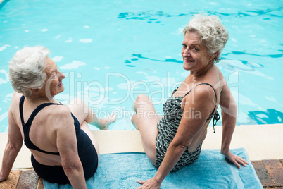 Two senior women sitting together at poolside