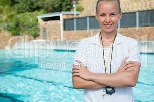 Female trainer standing with arms crossed at poolside