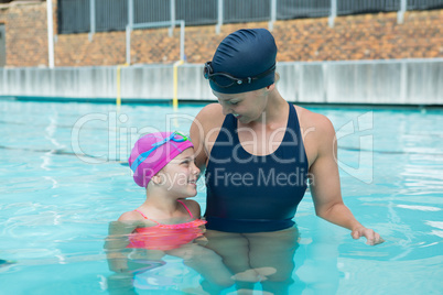 Female instructor and young girl relaxing in pool