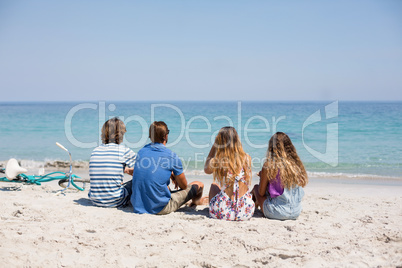 Rear view of friends sitting on during sunny day