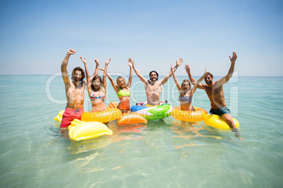 Friends enjoying on inflatable rings and pool rafts in sea
