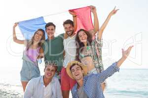 Friends holding French flag on shore at beach