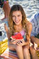 Happy woman having watermelon while sitting at beach