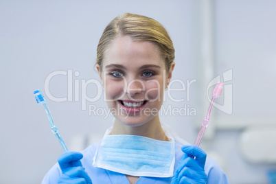 Portrait of female nurse holding toothbrushes