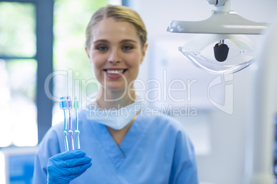 Portrait of female nurse holding toothbrushes