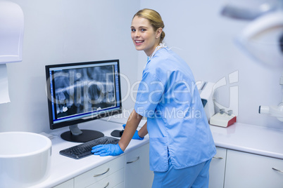 Portrait of female nurse examining x-ray report on computer