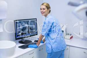 Portrait of female nurse examining x-ray report on computer