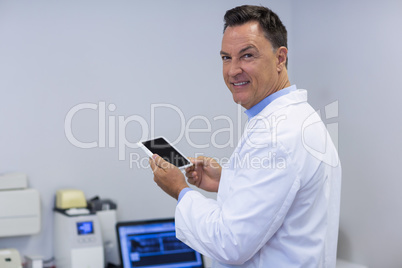 Portrait of smiling dentist holding digital tablet