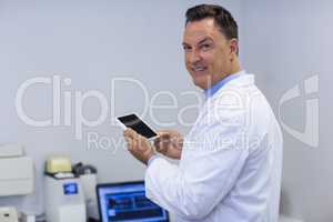 Portrait of smiling dentist holding digital tablet