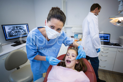 Dentist examining a young patient with tools