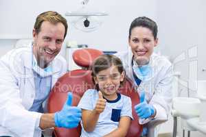 Portrait of smiling dentists and young patient showing thumbs up