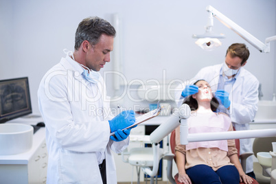 Dentist writing on clipboard