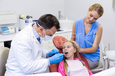 Dentist examining a young patient with tools