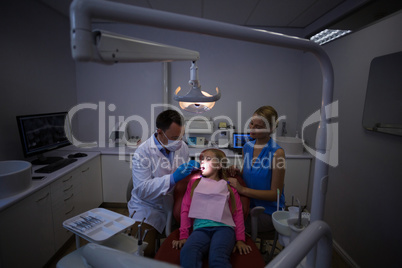 Dentist examining a young patient with tools