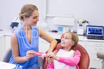 Mother giving tooth brush to daughter at dental clinic