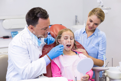 Dentist examining a young patient with tools