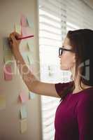 Woman  writing on sticky note by window