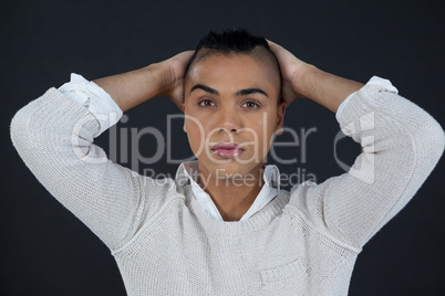 Transgender woman with hands behind back against black background