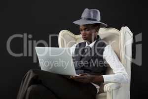 Androgynous man using laptop while sitting on a chair