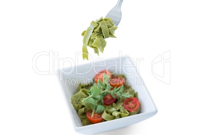 Pasta salad in bowl with fork on white background
